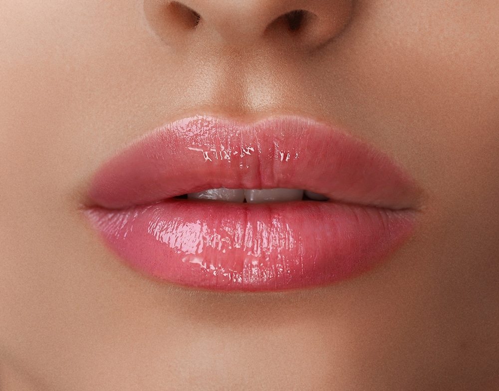 Closeup photo of a woman's lips with nude lipstick and gloss