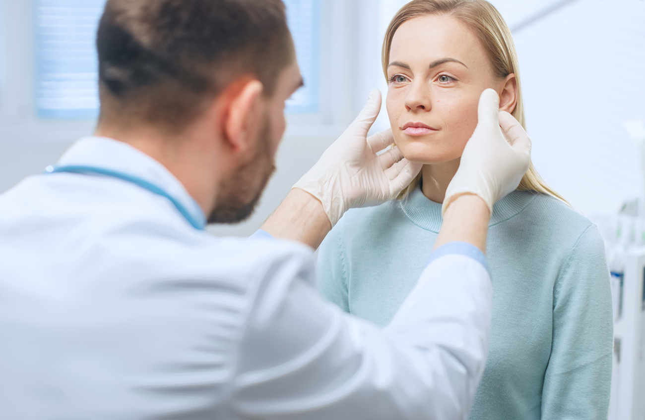 Doctor examining a woman's face during a medical consultation.